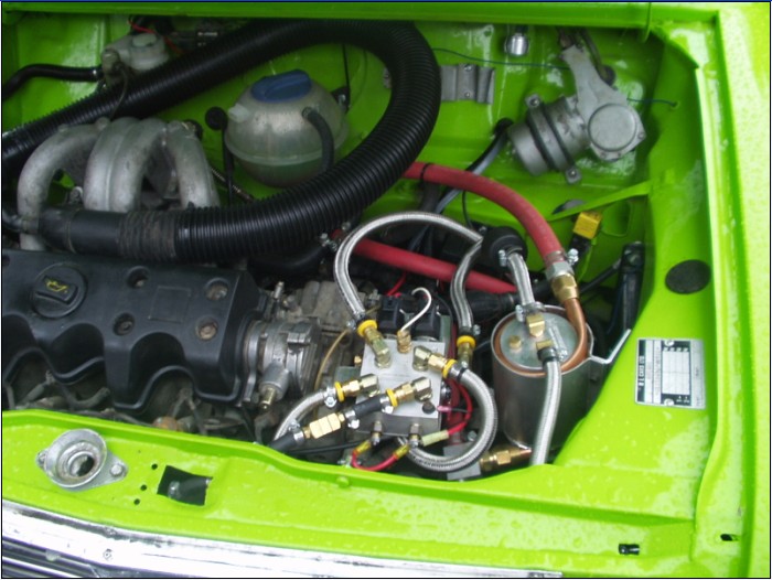 Přídatný palivový systém (palivové potrubí a filtr paliva vyhřívané chladicí kapalinou, přepínací ventily) instalovaný na motoru Peugeot v automobilu Austin Mini
